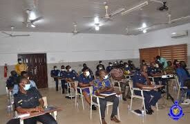 Officers of the Ghana Police Service seated in an examination hall or training setting