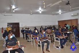 Officers of the Ghana Police Service seated in an examination hall or training setting